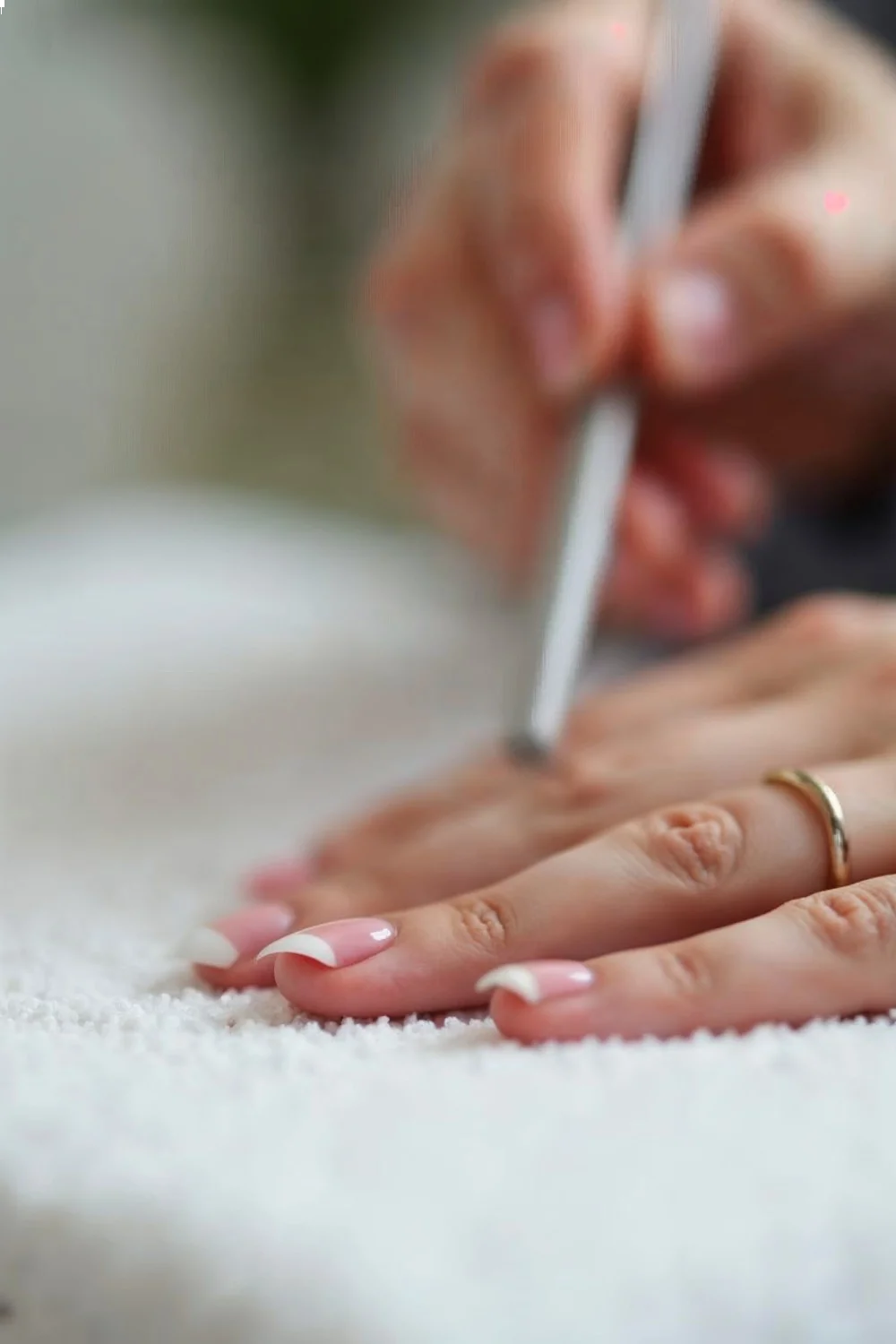 Close-up of a hand shaping coral pink french tips with a file, demonstrating control for acrylic fill at home