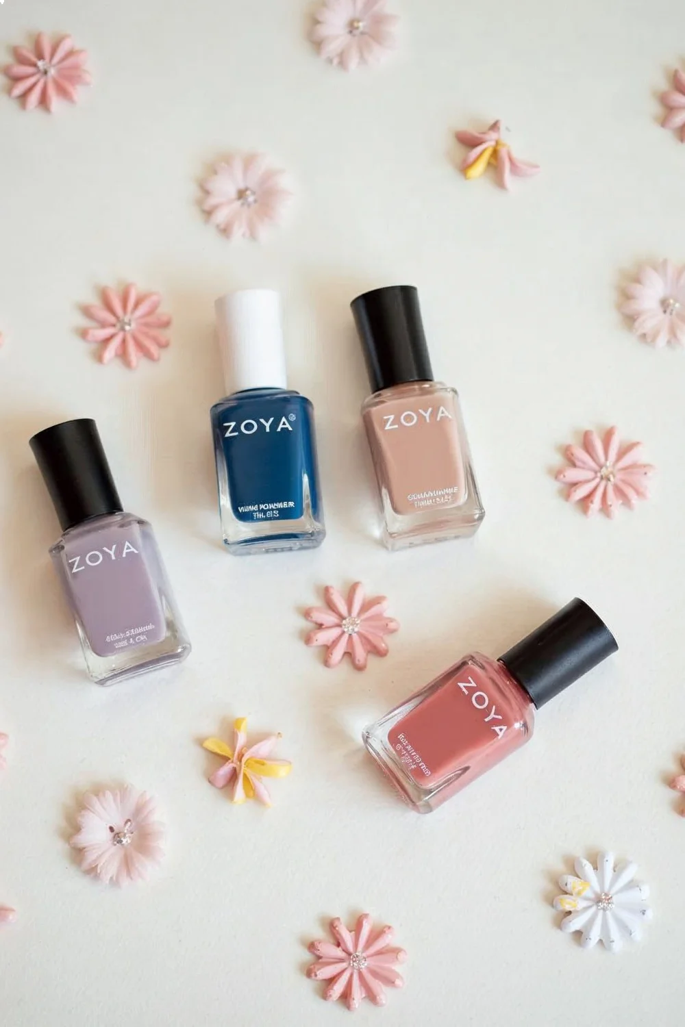 Flat lay of pregnancy-safe nail products including Zoya, Ella+Mila, and Tenoverten polishes arranged with baby shower decorations