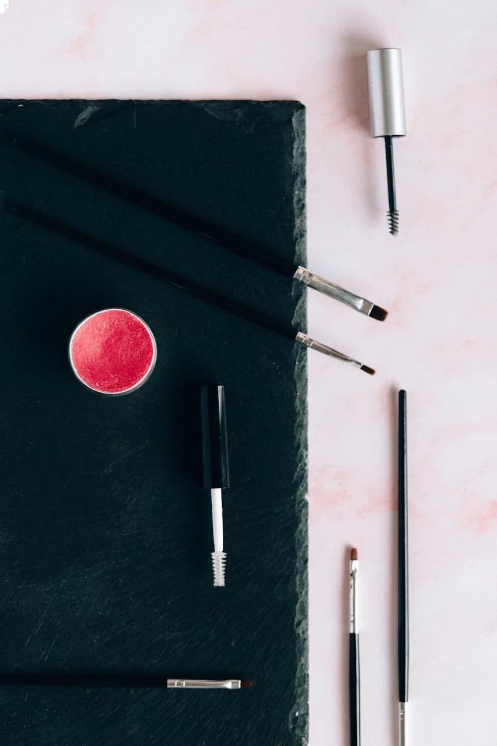 Flat lay of beach nails tools including jelly polishes, chrome powders, and various brushes on a white surface
