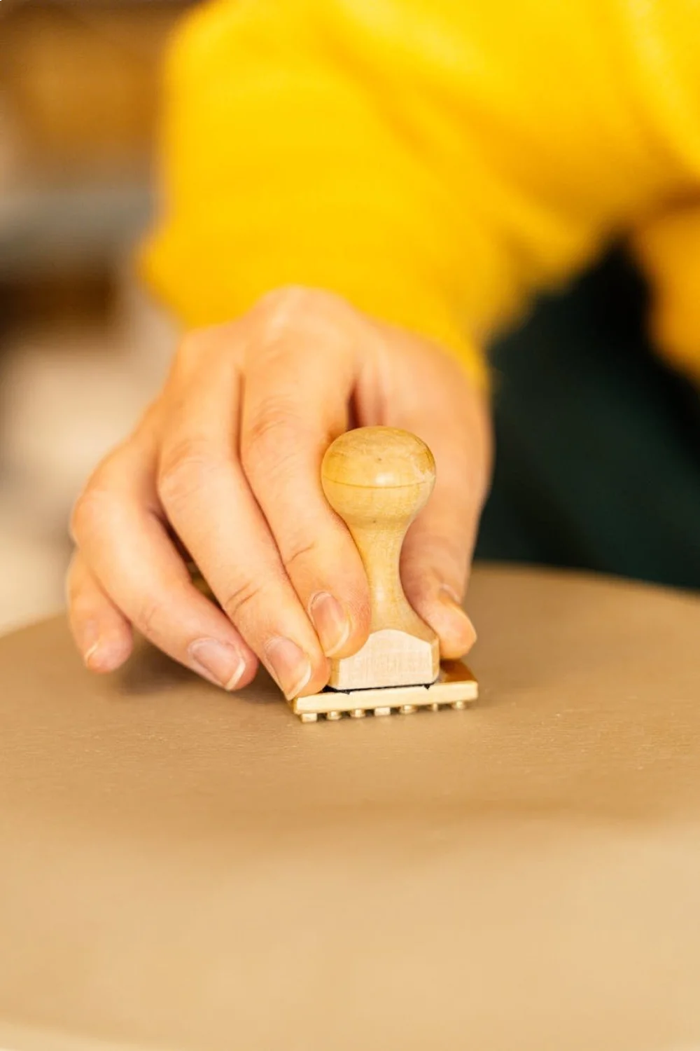 Hand pressing a wooden stamp onto a nail design plate with coral and ocean blue colors for beach nails