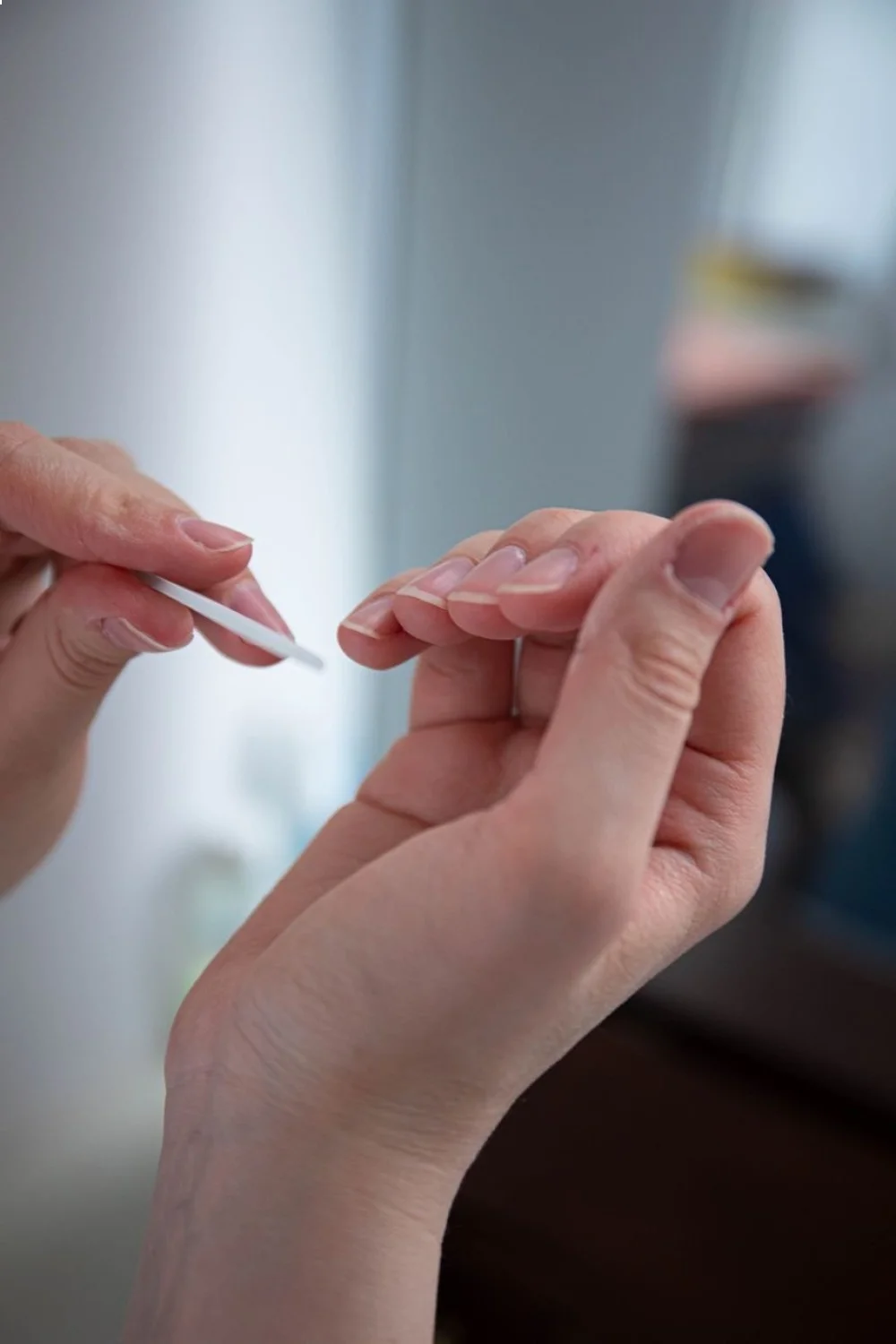 hands gently removing gel polish from healthy natural nails with a wooden stick