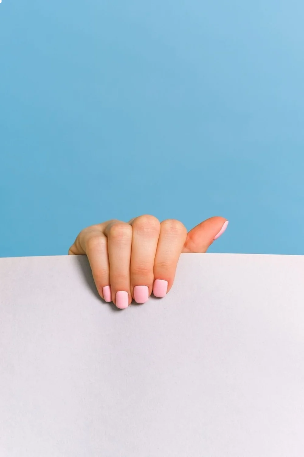 coral pink half-moon manicure with a clean line against a light background showcasing easy pretty nail designs