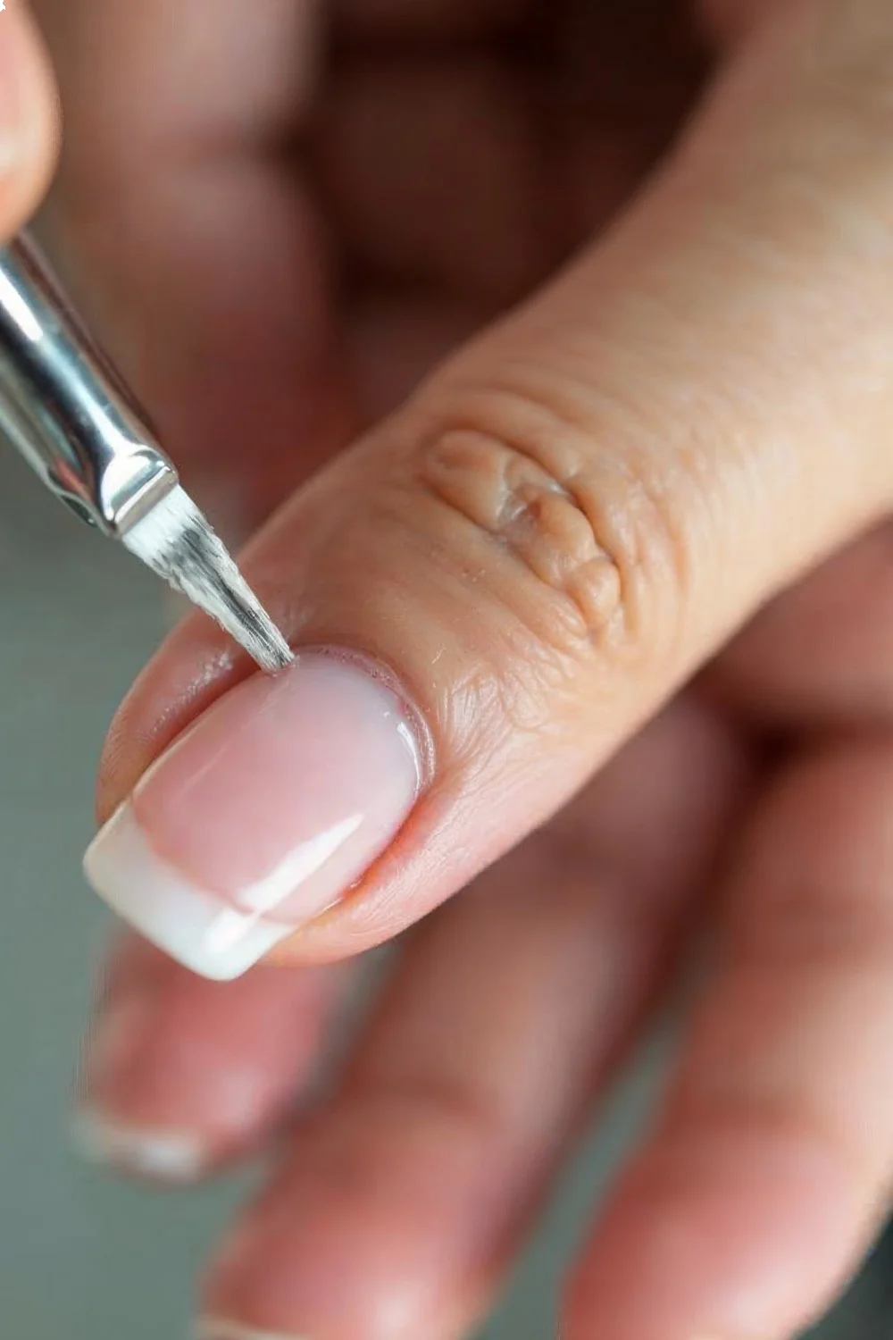 Close-up of a hand applying builder gel to a broken corner of a nail, demonstrating how to fix broken nails