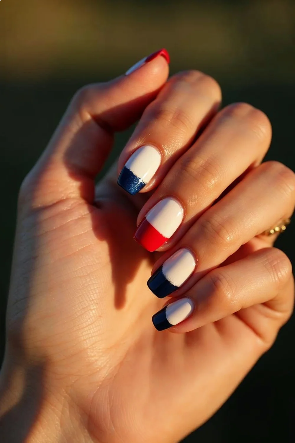 Half-moon manicure with red tips, white base, and navy accent nail showcasing fourth of July nails design