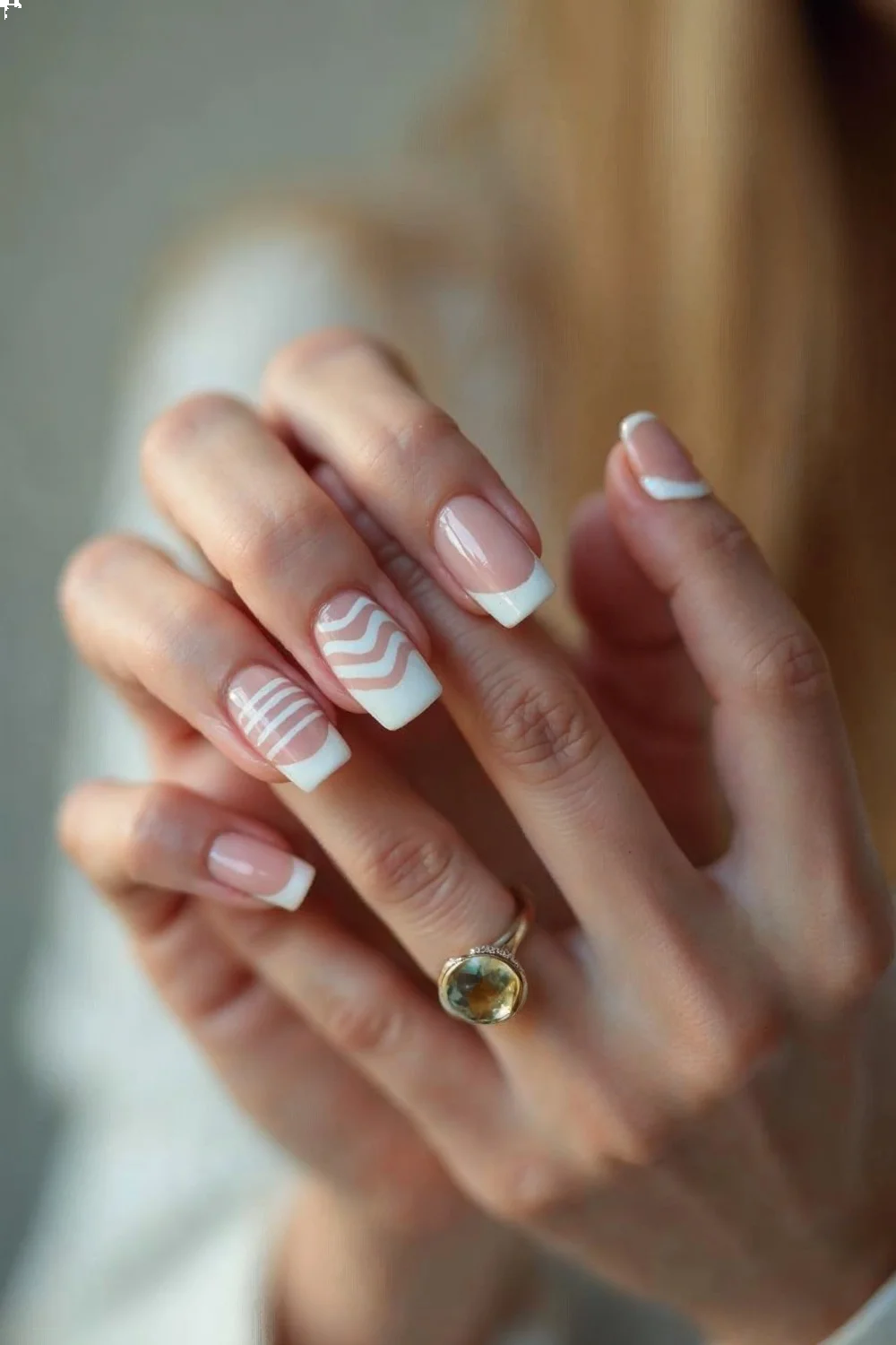 Coral pink French tips with wavy white lines on almond nails in a hand pose for a French manicure tutorial