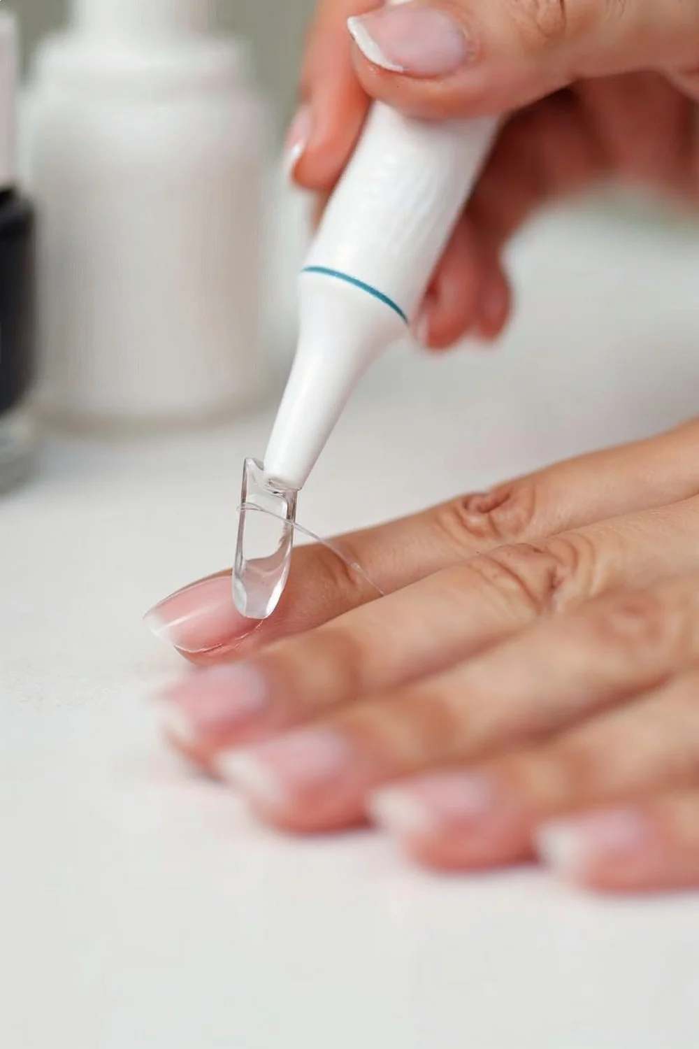 Close-up of a hand using a cuticle pusher at an angle to lift gel nail sheets during gel nail removal at home