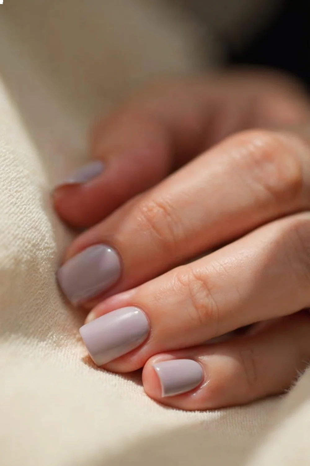 soft lavender matte nails with a smooth finish on a neutral fabric background