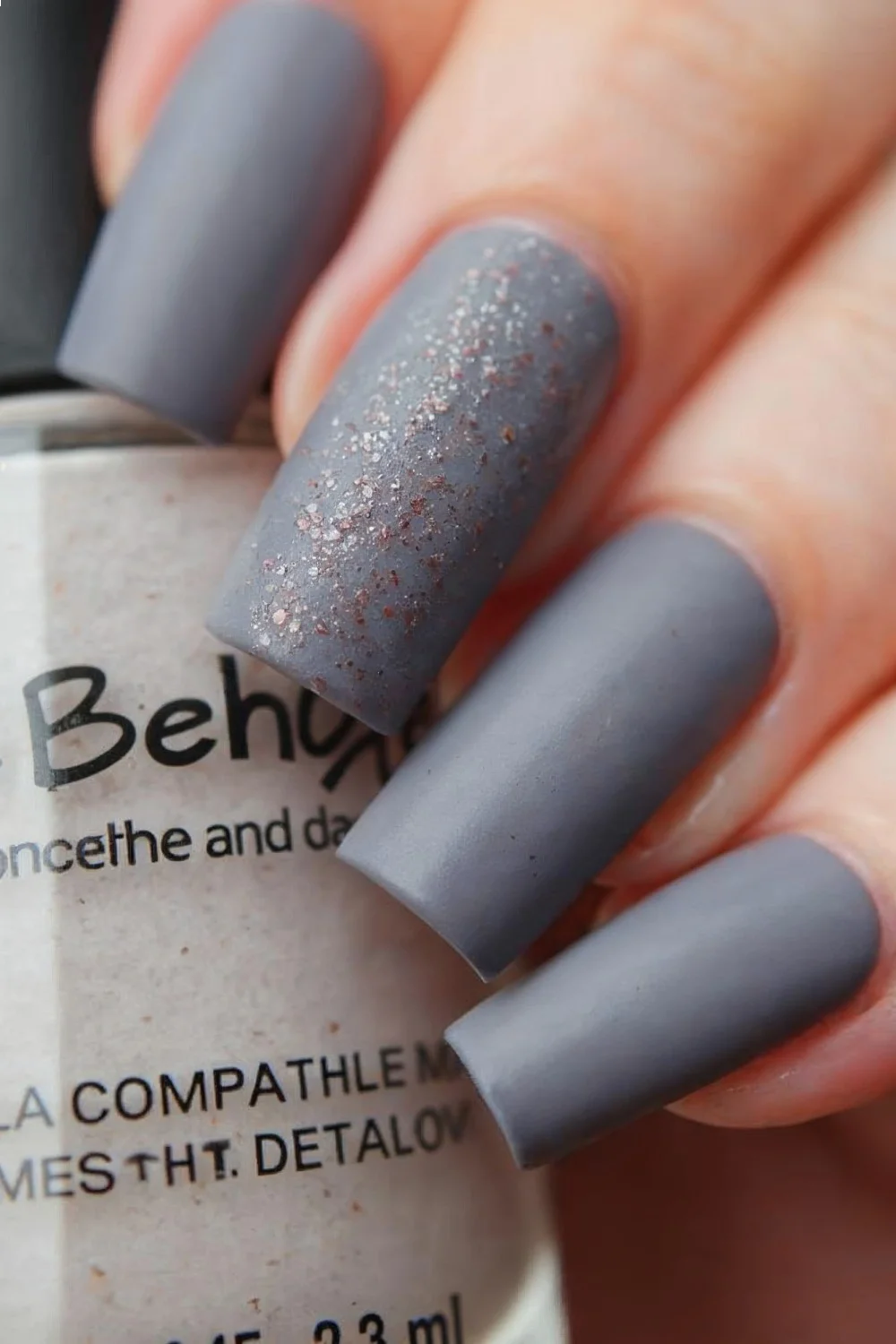 Matte nails in a soft gray shade with a subtle glitter accent on the ring finger