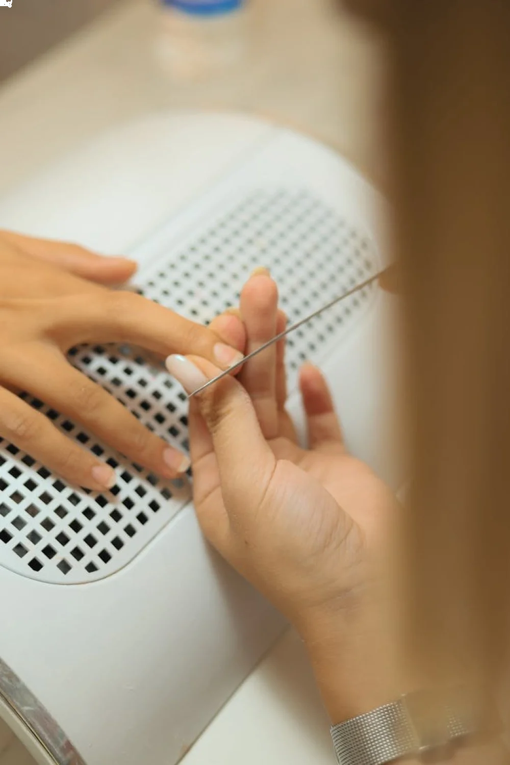 Wooden cuticle stick at 45-degree angle against nail base, demonstrating proper pushback technique for press on nails