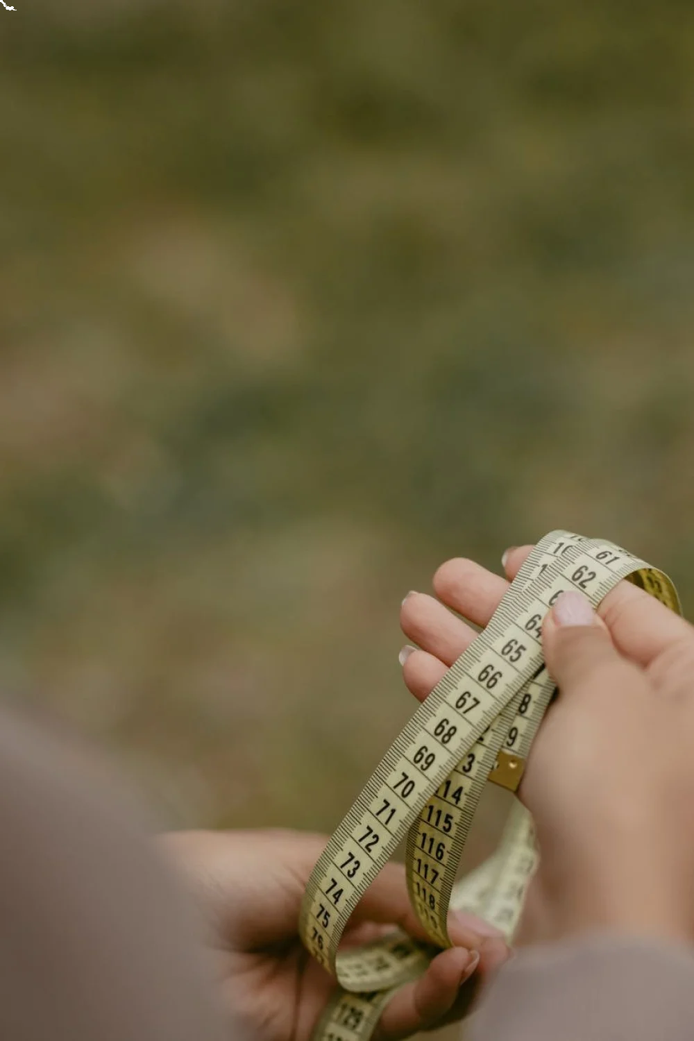 Hand holding a fabric measuring tape across a nail bed, measuring for press on nails