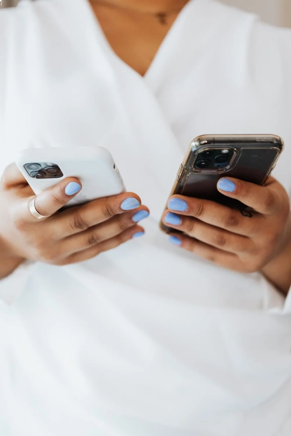 hands holding two smartphones with light blue squoval nails
