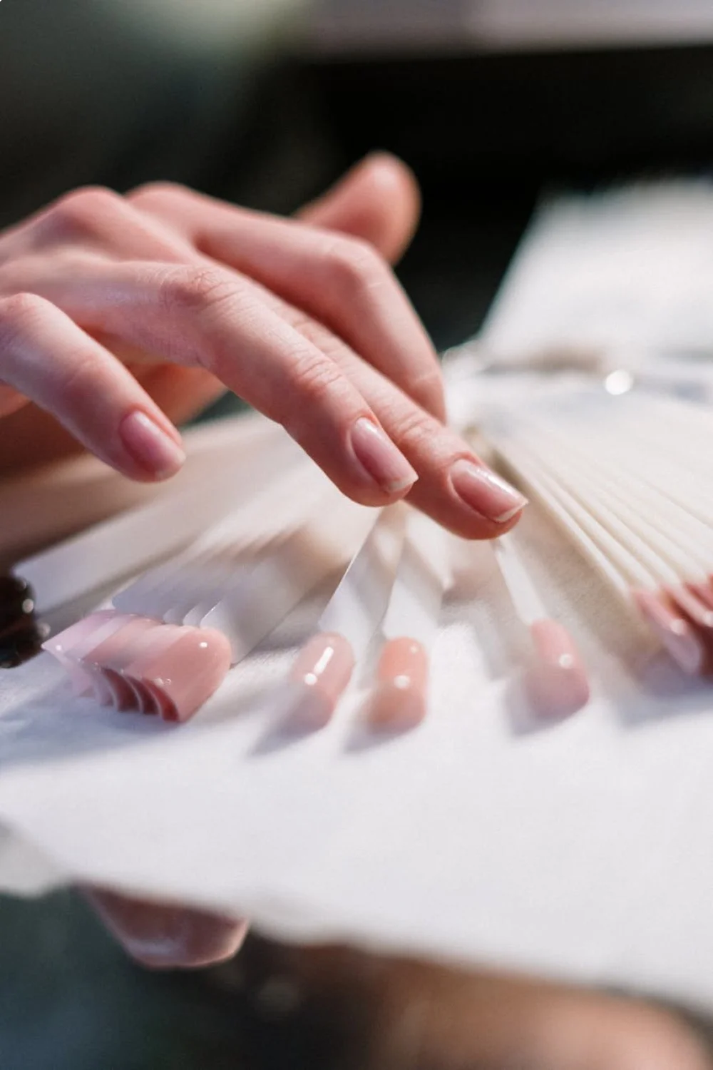 Close-up of hand with smooth, buffed nails and white base coat, preparing for sunset nails gradient techniques